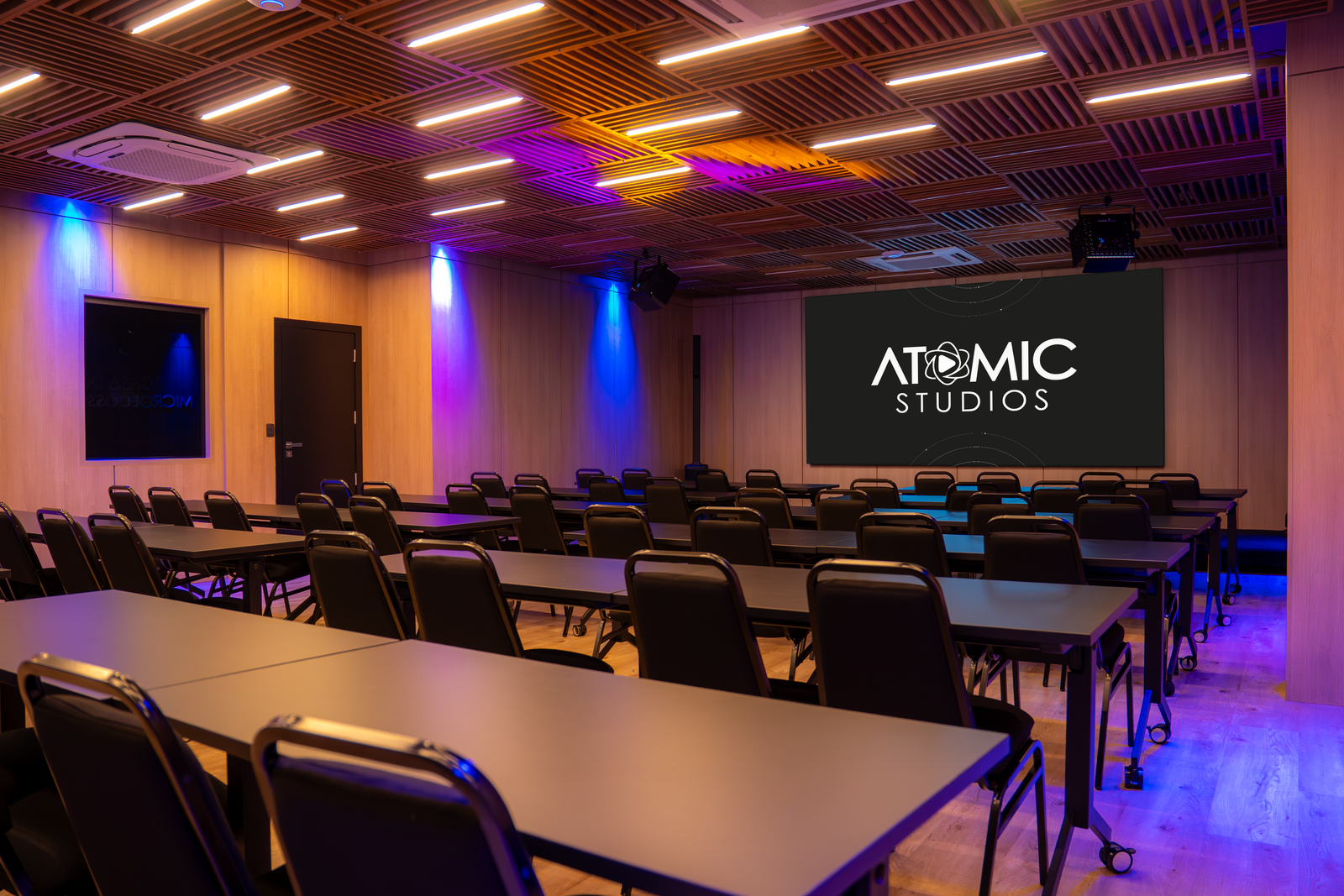 Auditório da Atomic Studios com telão e iluminação quente