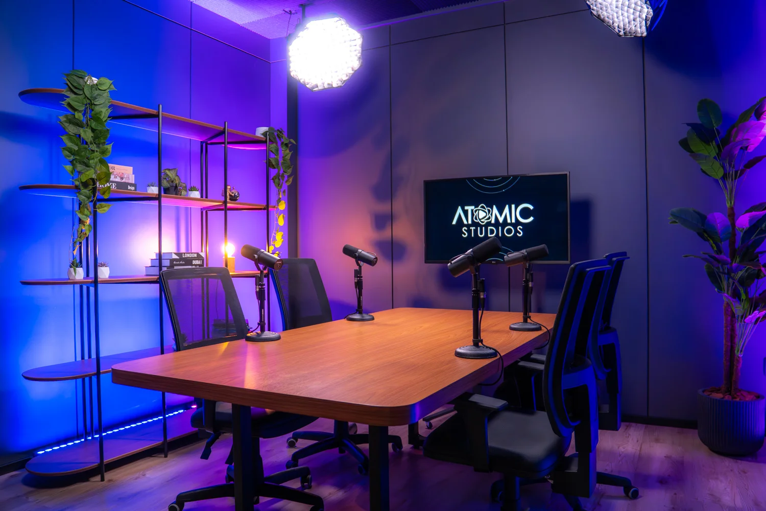 Mesa de podcast com microfones e telão Atomic Studios